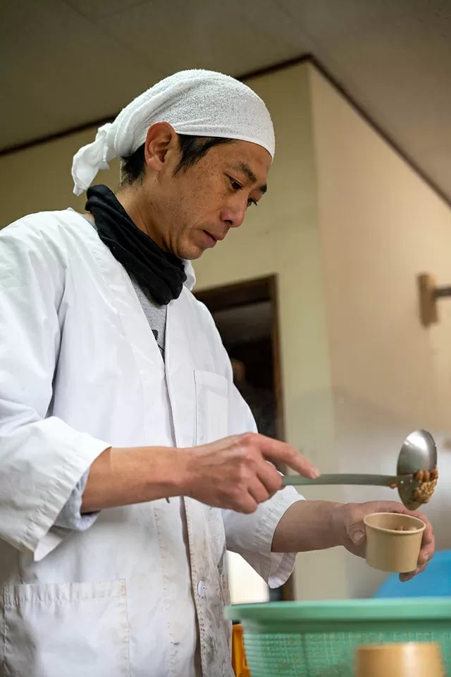 ザルからおたまですくって容器に1個1個入れていく